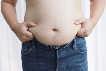 Naklejka premium Man with fat belly in dieting concept. Overweight man touching his fat belly and want to lose weight.