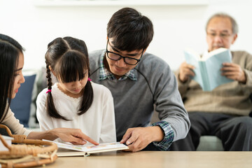 Fototapeta premium Daughter reading story with multigenerational family