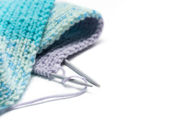 Knitted scarf and knitting needles close-up, on a white background with copy space.