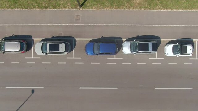 AERIAL, TOP DOWN: High-tech self-steering vehicle parks itself into empty roadside parking spot. Flying above an autonomous car successfully parallel parking into a vacant spot at the side of a road.