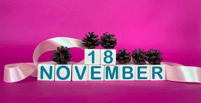 November 18 on wooden cubes on a pink background.Autumn calendar for November.