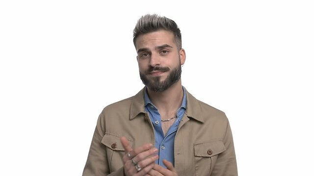 Clueless Young Man In Denim Shirt Rubbing Palms, Looking To Side, Shrugging And Having No Idea, Pointing Finger To Back, Pulling The Ear Lobe And Listening, Vaguely Looking Behind On White Background