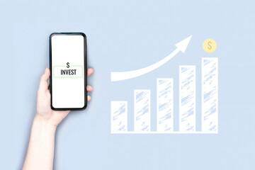 Obraz na płótnie Canvas Hand holding smartphone with invest sign. Financial chart is rising up. White ladder statistics with arrow up. Business flat lay on blue background. Career success. Save Investment. Money profit