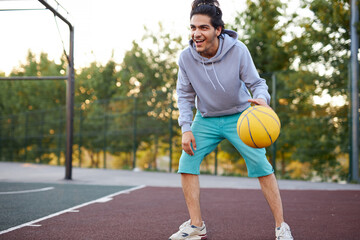 Obraz premium athletic young boy in casual wear keen on basketball, enjoy playing outdoors, sport concept
