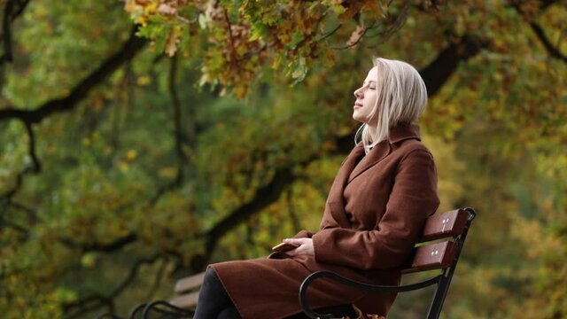 Woman sitting on a bench in a autumn park