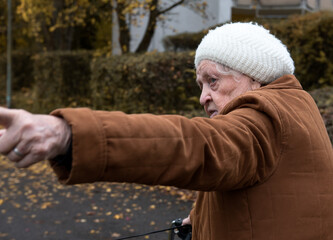Elderly woman taking a walk in autumn with walker aid to enjoy fresh air