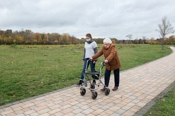 Elderly woman taking a walk with granddaughter with the help of a walker in winter