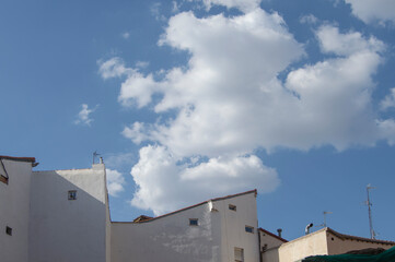several white facade buildings and rooftops with a sky with white clouds above