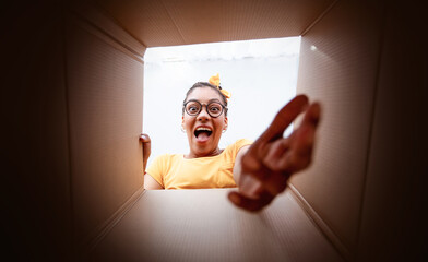 Excited african woman in glasses unpacking carton box