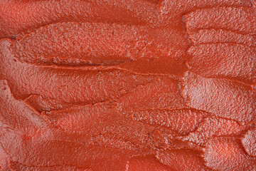 Texture of red tomato paste with streaks.
