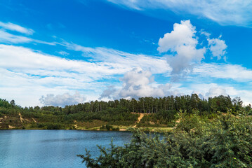 White clouds in the blue sky over the lake in summer.
