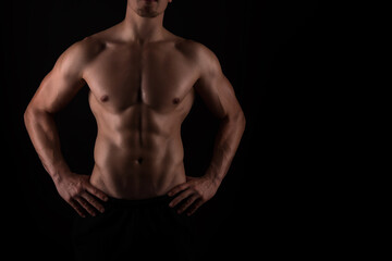 Fototapeta na wymiar Muscular male torso of fit bodybuilder on black background