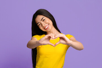 Cheerful young korean woman shaping hands like heart, showing love gesture