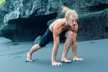 Fototapeta na wymiar Athlete man practicing on a black sand beach