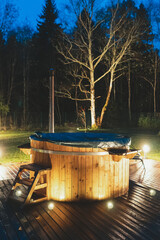 Wooden hot tub with fireplace at night.