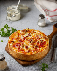 Shortcrust quiche with chanterelle mushrooms and cheese on a wooden board on the table, close-up