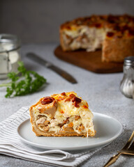 Slice of quiche lauren pie with mushrooms, chicken and cheese on a plate on a gray table