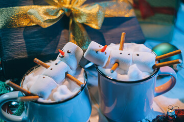 a mug with hot chocolate on a wooden table with a marshmallow man who is resting in a mug