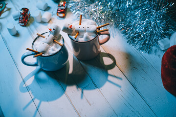 a mug with hot chocolate on a wooden table with a marshmallow man who is resting in a mug
