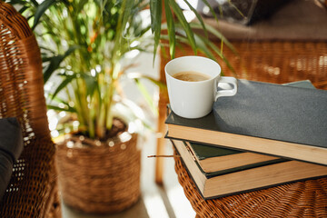 Warm and soft hotel room with custom design there are table with coffee cup and books on it and bamboo chairs with pillows.