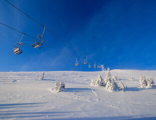 Fototapeta na wymiar Alpine resortr ski lift with seats going over the sunrise mountain skiing freeride slopes and fir tree groves
