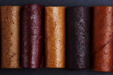 Colorful fruit rolls on dark background
