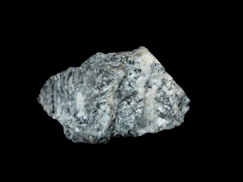 Sample of raw white with black inclusions of magnesite on a black background