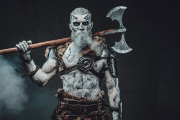 Risen from the dead northern warrior in smokey background with huge two handed axe on his shoulders...