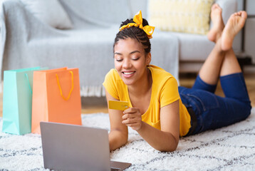 Black woman using laptop and credit card on the floor