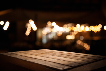 empty wooden table on blurred light gold bokeh of cafe restaurant on dark background