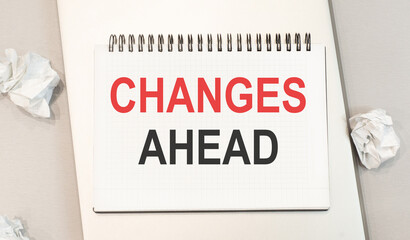 Text changes ahead written in a notebook that sits on a gray desktop along with a laptop. Business concept
