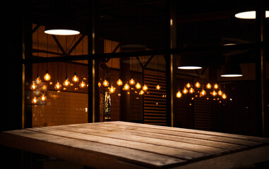 empty wooden table on blurred light gold bokeh of cafe restaurant on dark background