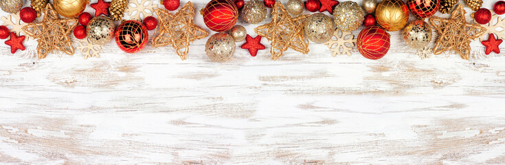 Christmas top border of red and gold ornaments. Overhead view on a white rustic white wood banner background. Copy space.
