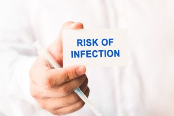 Word risk of infection on a white background with a syringe in hand. Medicine concept