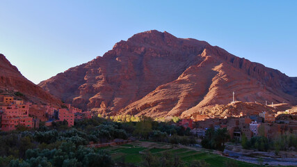 Small Berber village near Tinghir, Morocco at the entrance of famous Todgha Gorges in the Altas Mountains with red colored rocks in the morning sun.