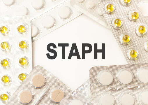 Text staph on white background. There are various pills and vitamins around. Medical concept