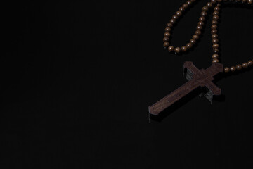 Wooden christian cross necklace on black background