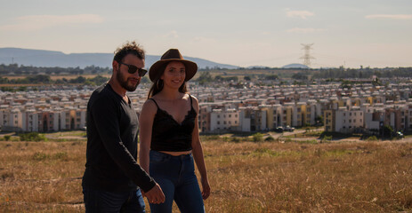 A romantic and lovely latin couple walking and posing in a beautiful sunny day with a dry grass field in the background