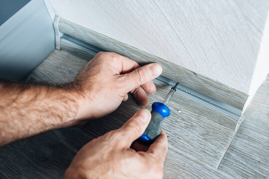 Installation Of A Plastic Skirting Board With A Plastic Dowel To A Concrete Wall With Wallpaper - Rigid, Reliable Fastening Of The Floor Skirting Board To The Laminate