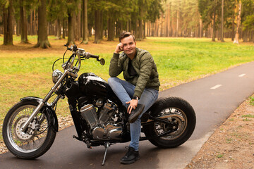 Beautiful man sits on a motorcycle, road