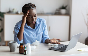 Sick black female office employee sitting at workplace taking lots of pills