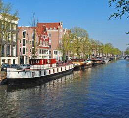 Cityscape in Amsterdam: river canal and boats at the waterfront