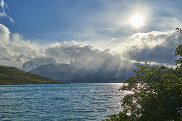 Towers of torres del Paine national park covered in clouds with dark green forest a lake and snow covered mountains of the Andes in Patagonia southern Chile