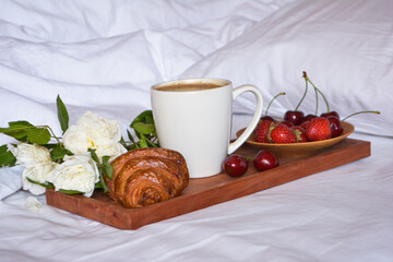 Breakfast in bed. Good morning. Wooden tray with a cup of coffee, croissant, berries.