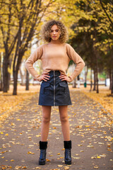 Obraz premium Portrait of a young beautiful girl in beige sweater and black skirt