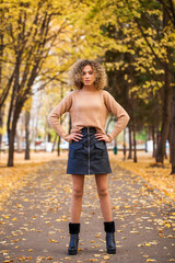 Portrait of a young beautiful girl in beige sweater and black skirt