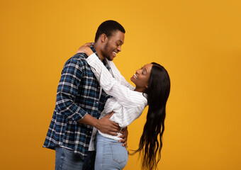 Smiling young african american man and lady have fun, hug and look at each other