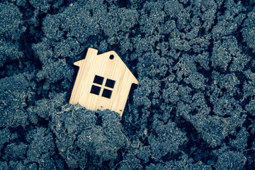 Naklejka premium Miniature wooden toy house standing in the cracked black ground close up. Mortgage, rent, realtor, real estate concept