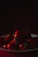 Cherry tomatoes on a white plate, shallow depth of field, dark dramatic effect