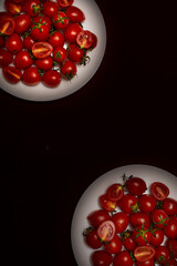 Cherry tomatoes on a white plate on a black background, top view